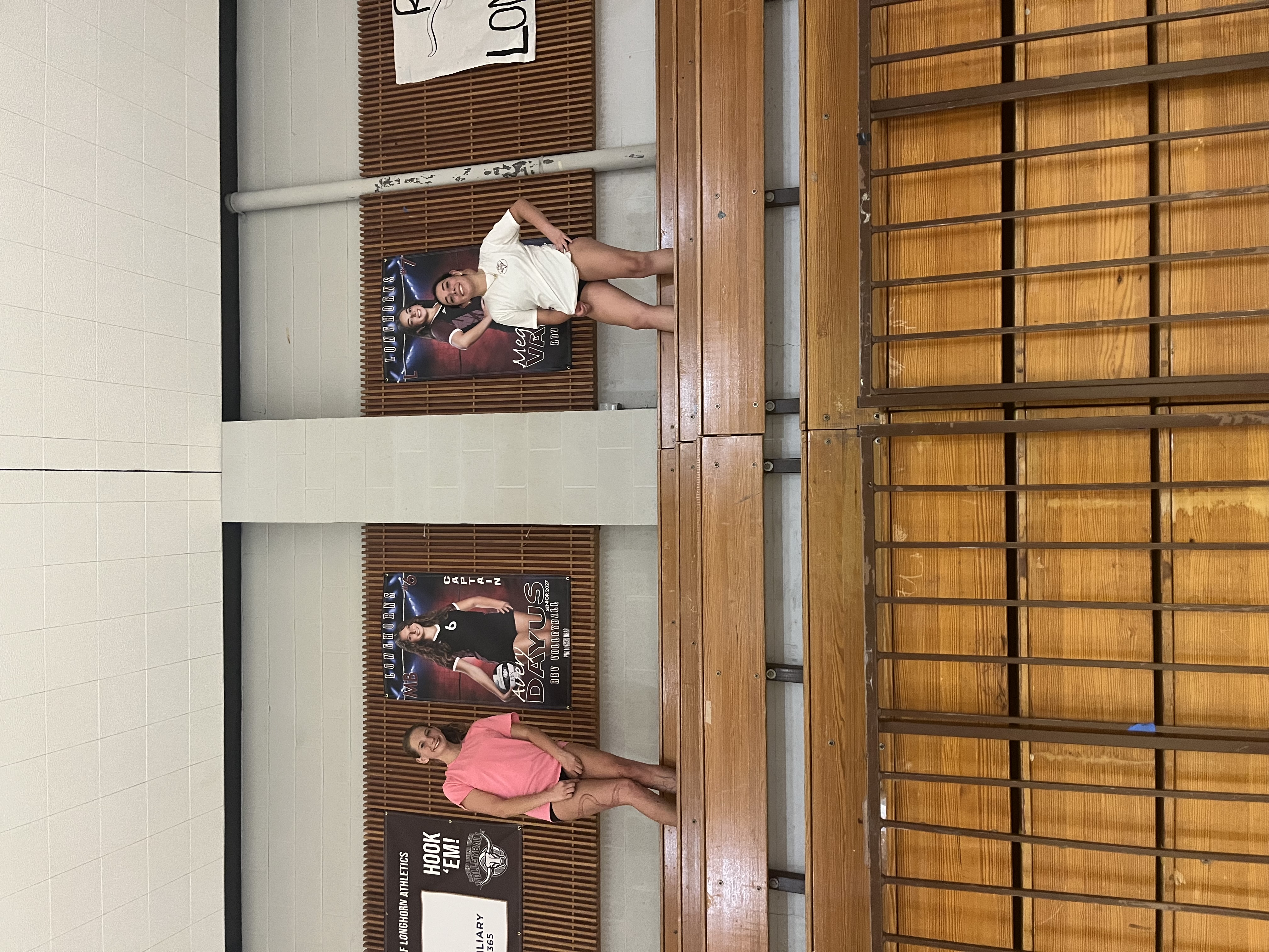 RBV volleyball players posing beside senior banners in the gym